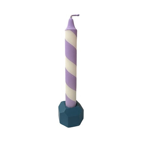 A pink cylindrical dinner candle holder with a lip around the bottom to catch any drips holding a blue dinner candle.