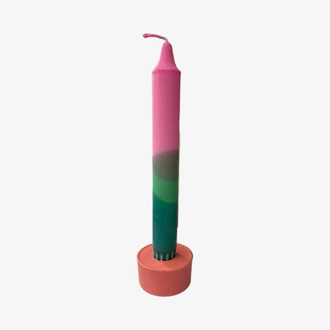A cylindrical dinner candle holder with a lip around the bottom to catch any drips holding a blue dinner candle.