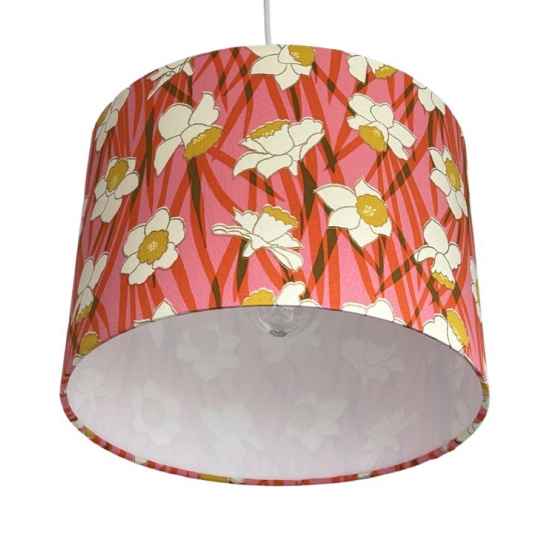 Drum lampshade covered in cotton fabric with a pink and red background and white and yellow daffodils