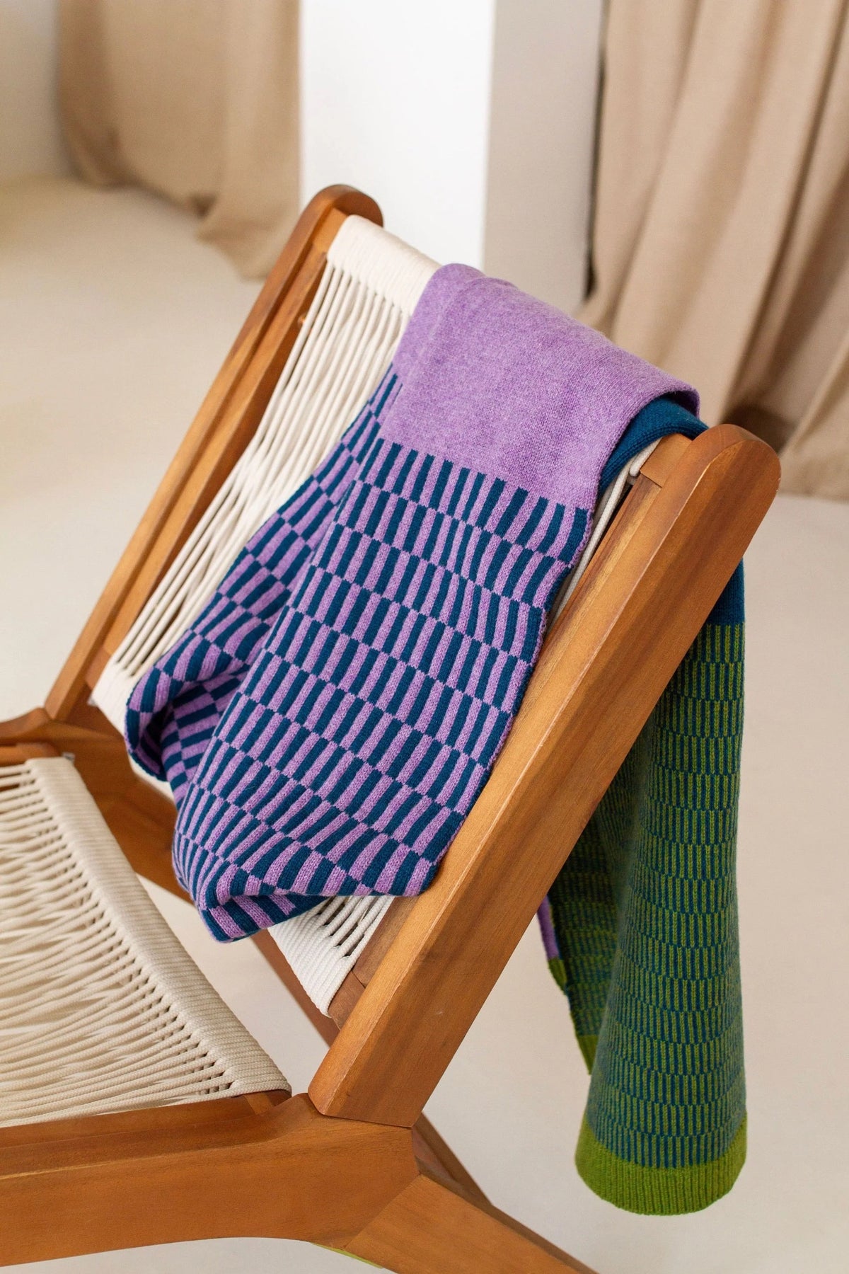 Wooden chair with a purple and green striped blanket scarf draped over it.