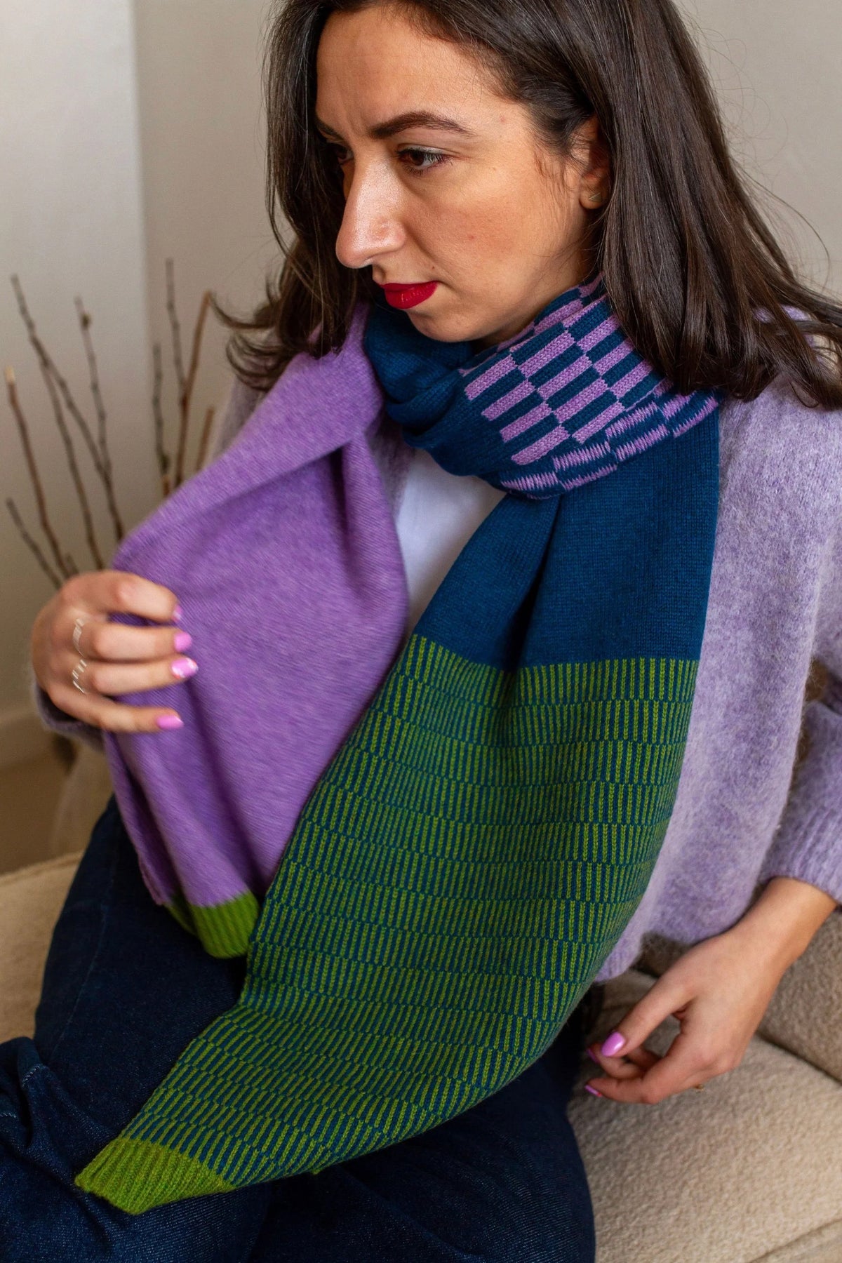 Woman wearing a colorful scarf with a neutral background.