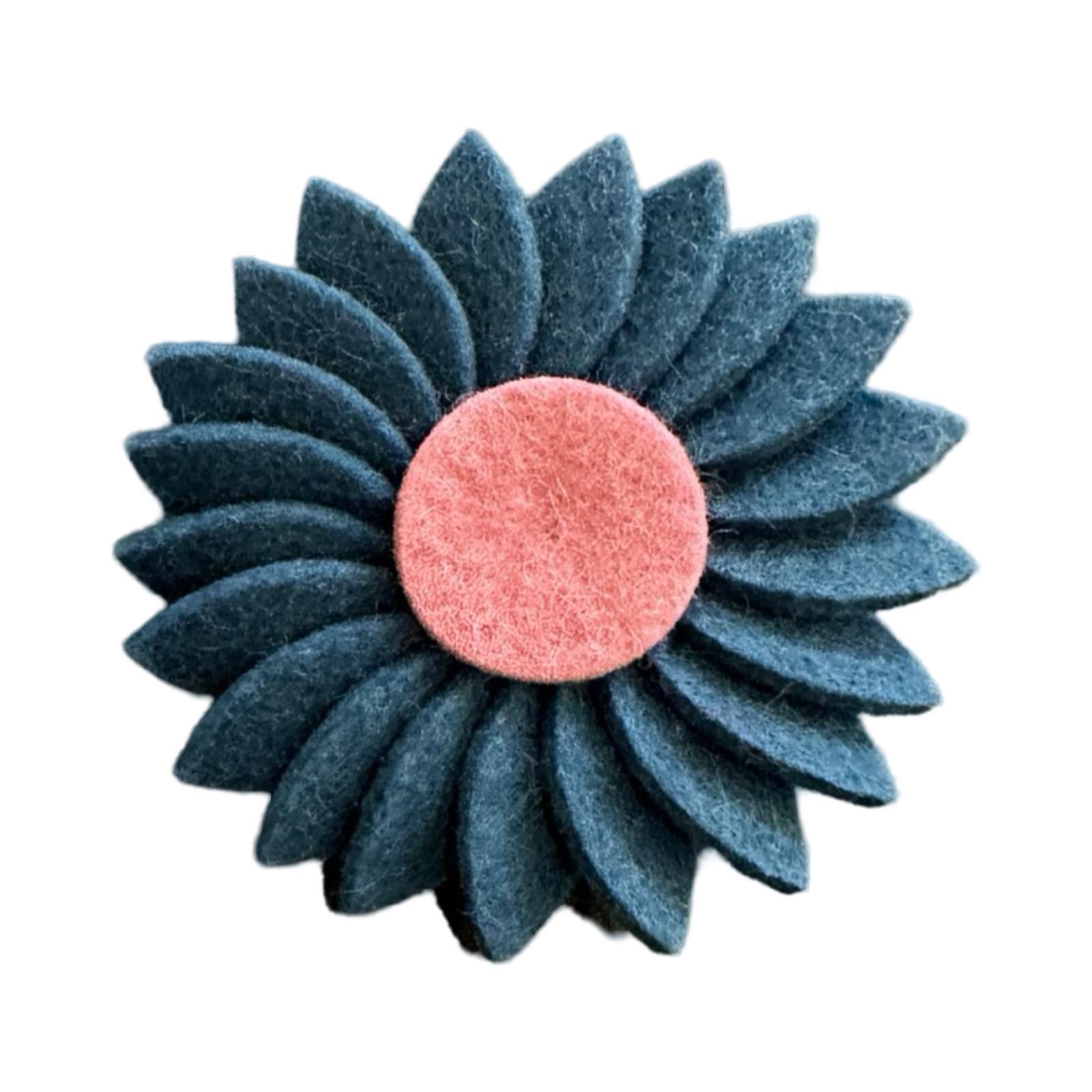 Handmade felt daisy-shaped brooch with a contrasting centre.