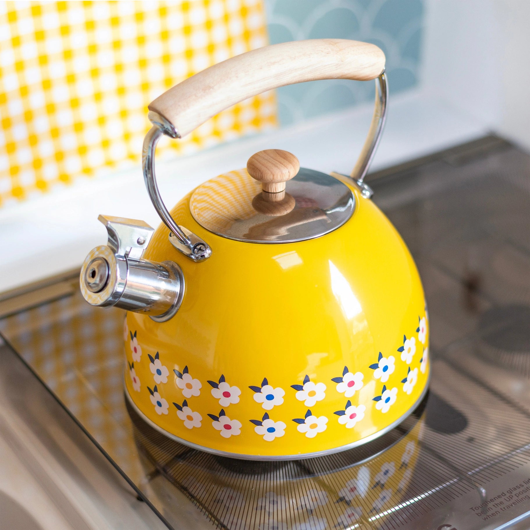 Yellow kettle with floral pattern on a stove.