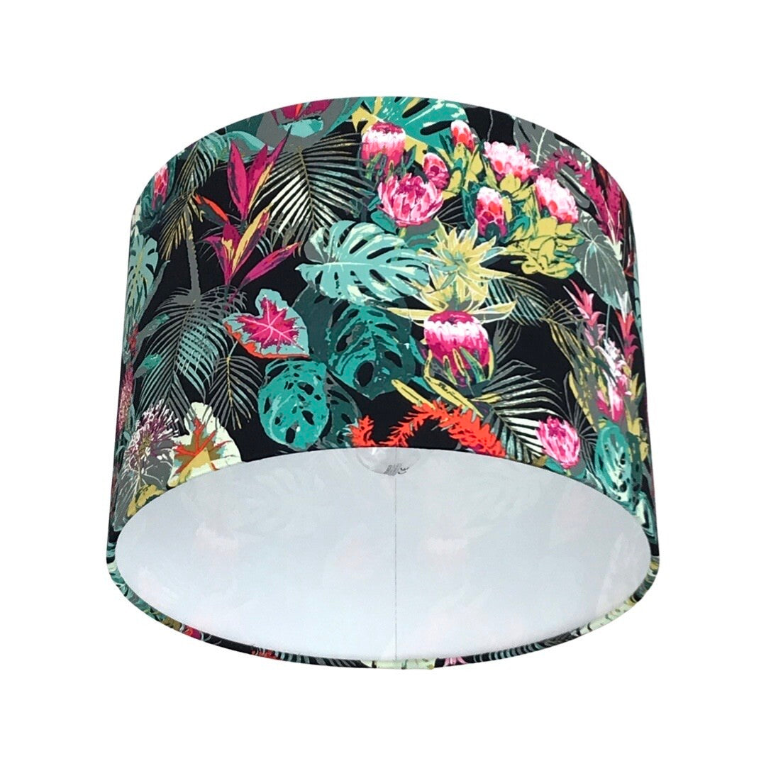 Close up of a drum lampshade covered in dark cotton fabric with bright tropical flowers and leaves