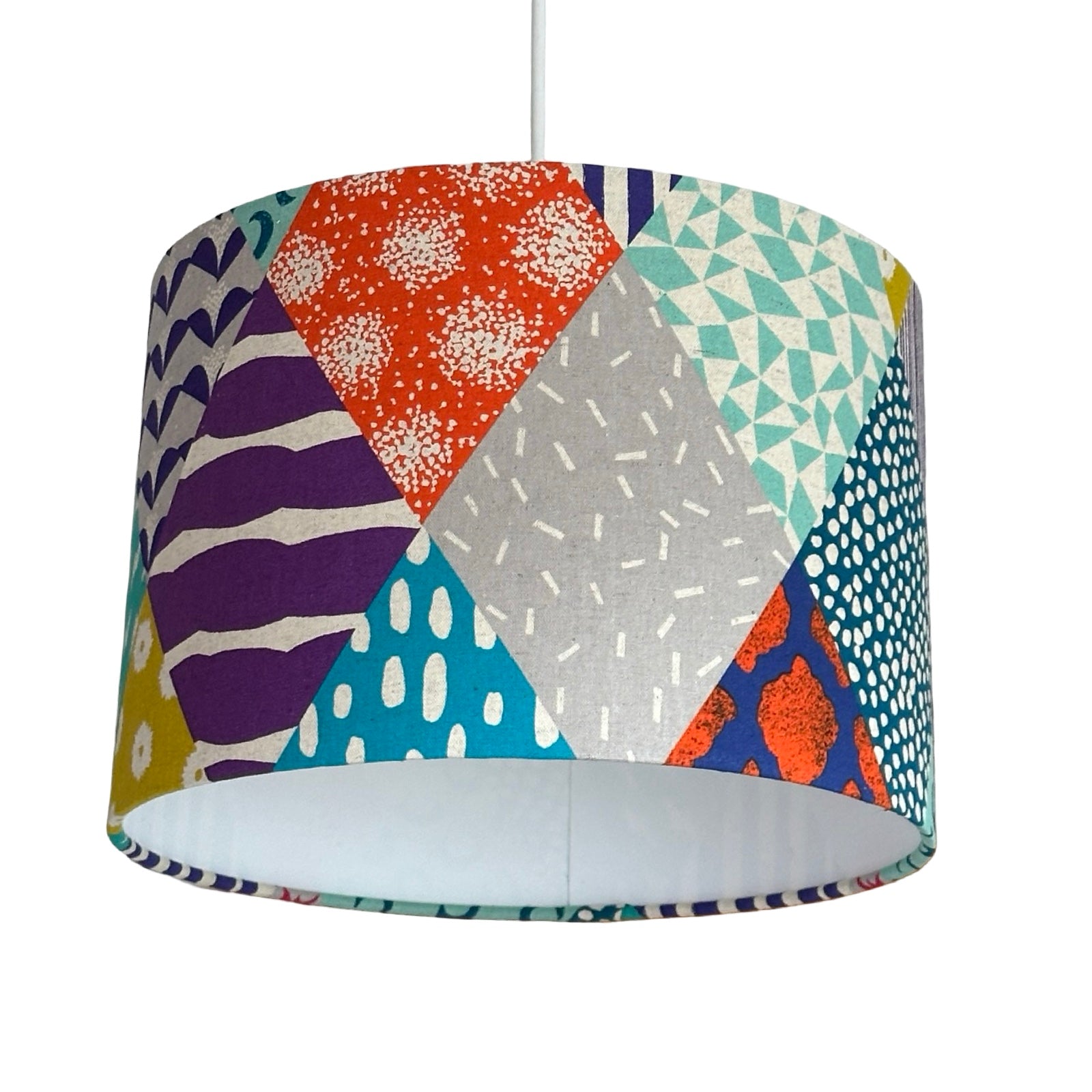 Colourful geometric patterned lampshade on a white background.