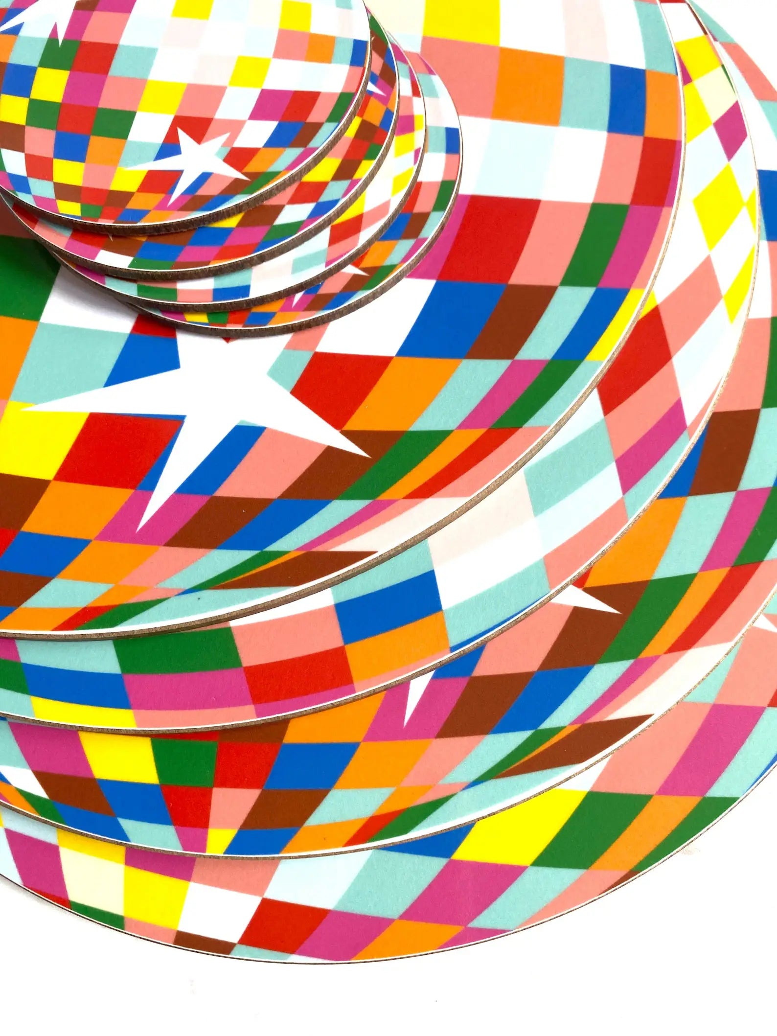 Colourful disco ball place mats stacked on a white background.