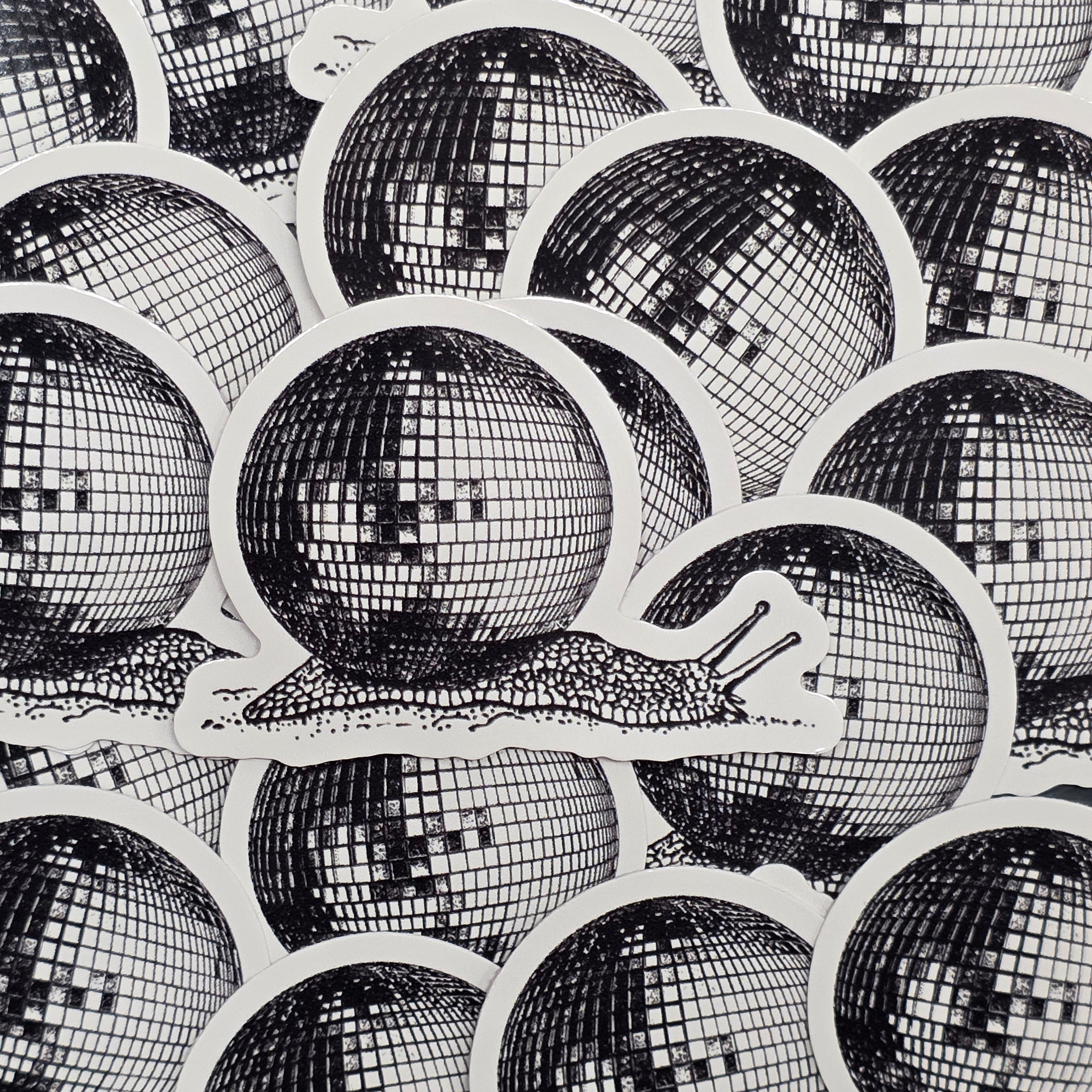 A waterproof vinyl sticker of a snail carrying a giant disco ball on its back.