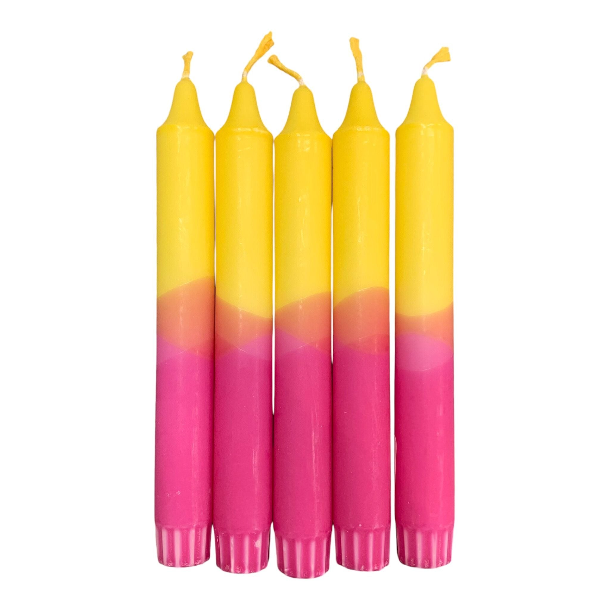 A row of 5 handmade dinner candles with a bright pink base and yellow top.