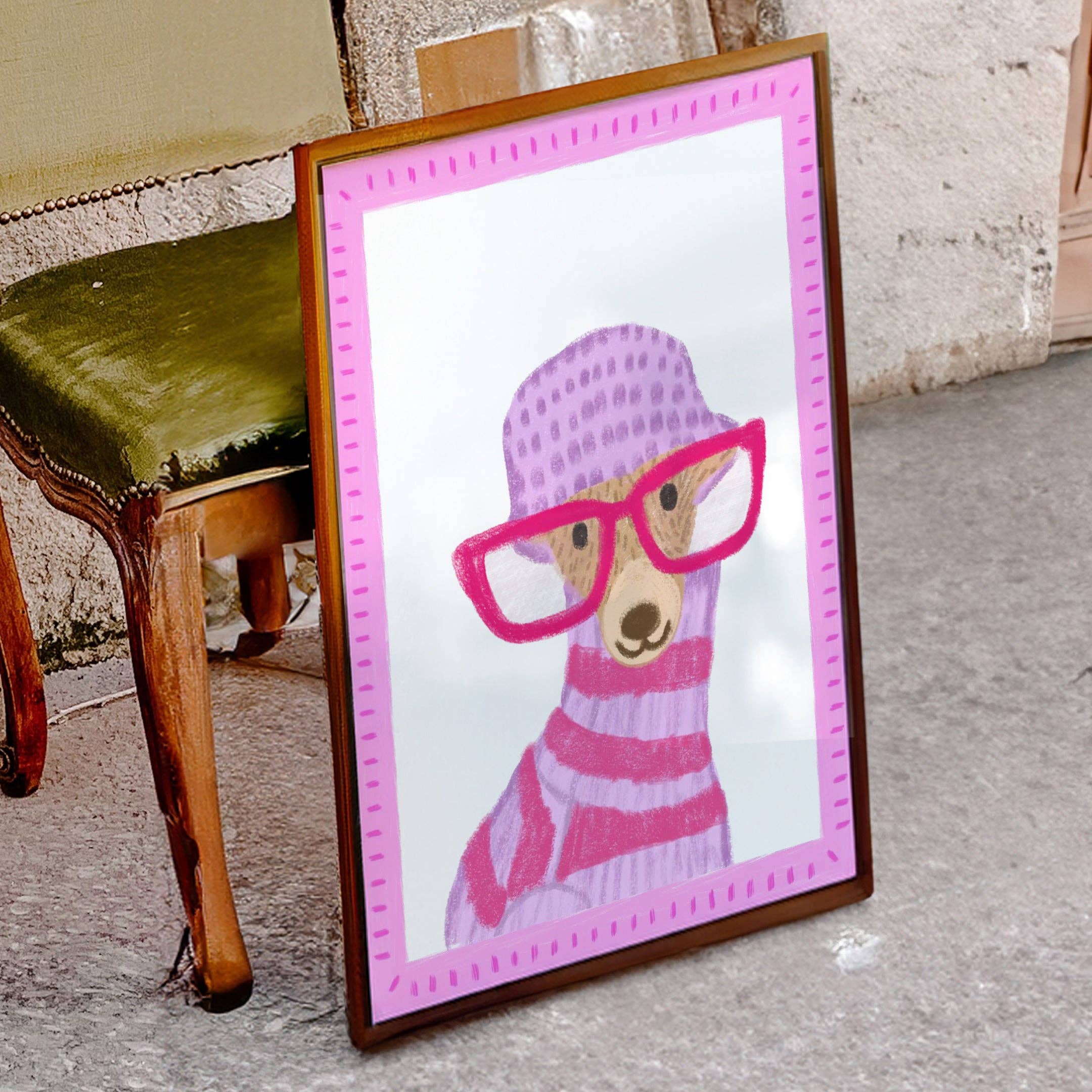 Framed artwork of a dog wearing pink glasses and a striped sweater on a purple background, against a chair.