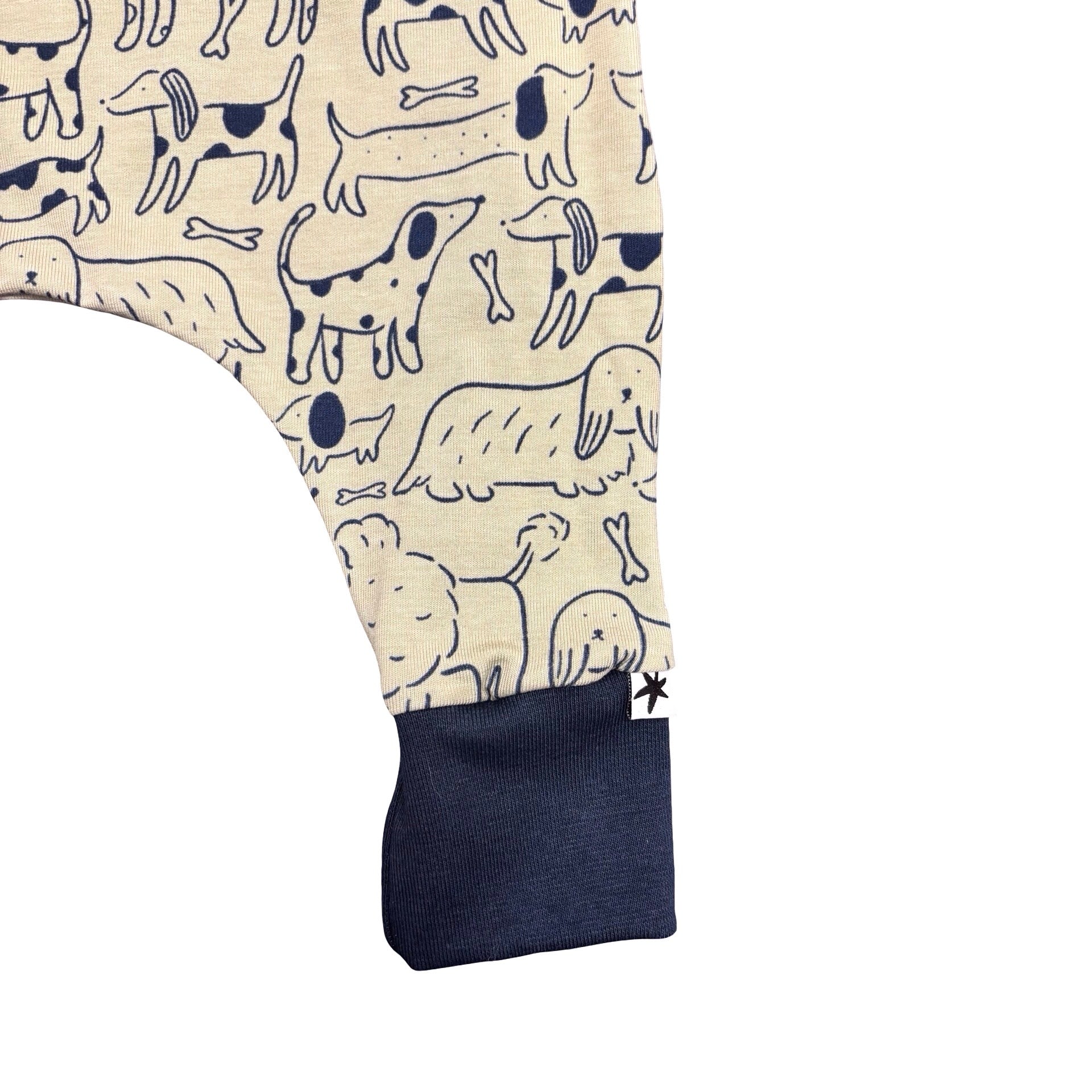 Kids romper with dog pattern on beige background with navy blue cuffs.