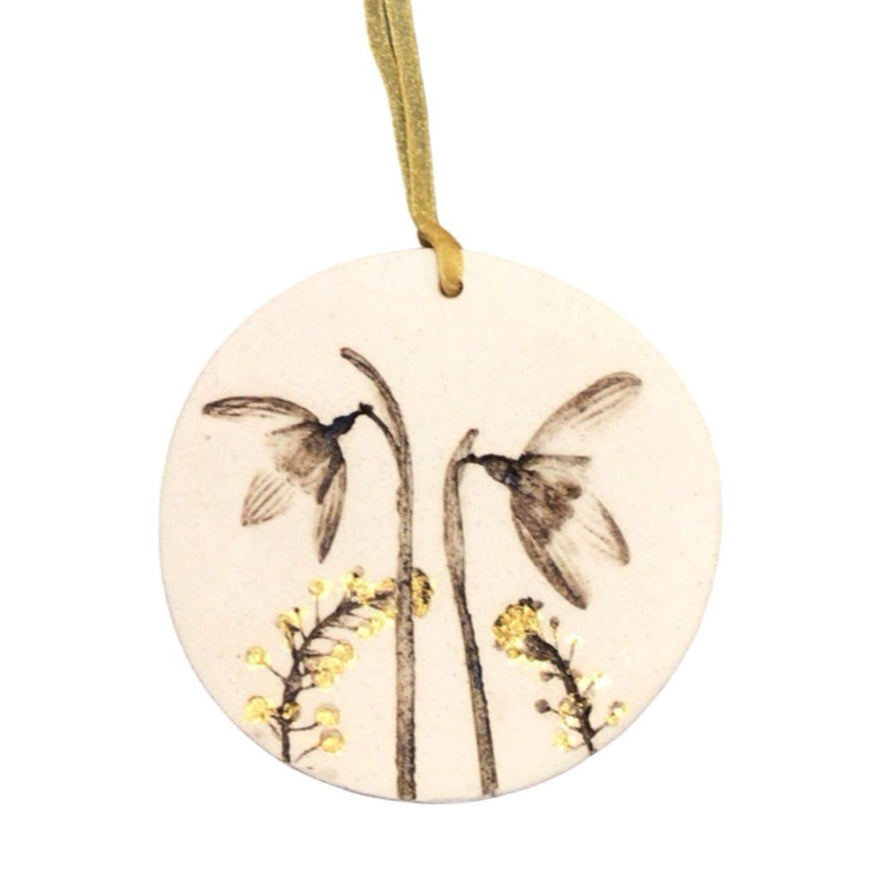 Round ceramic ornament with floral design and hanging string on a white background