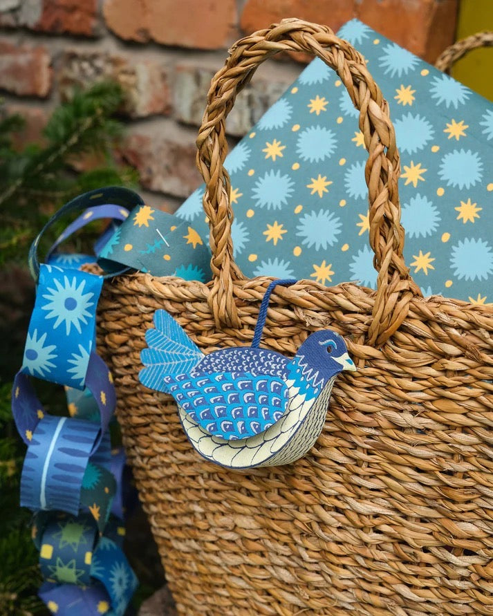 Wicker basket with a blue bird ornament and decorative paper chains against a brick wall.