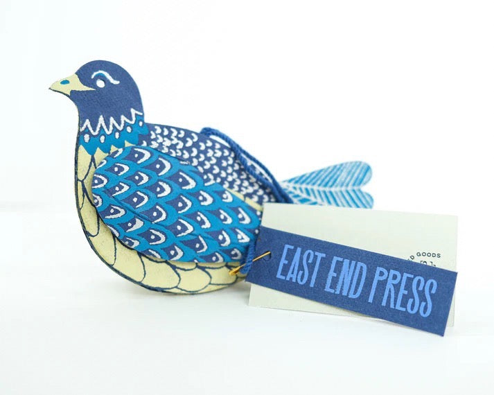 Blue and white patterned bird-shaped object with a 'East End Press' tag on a white background.