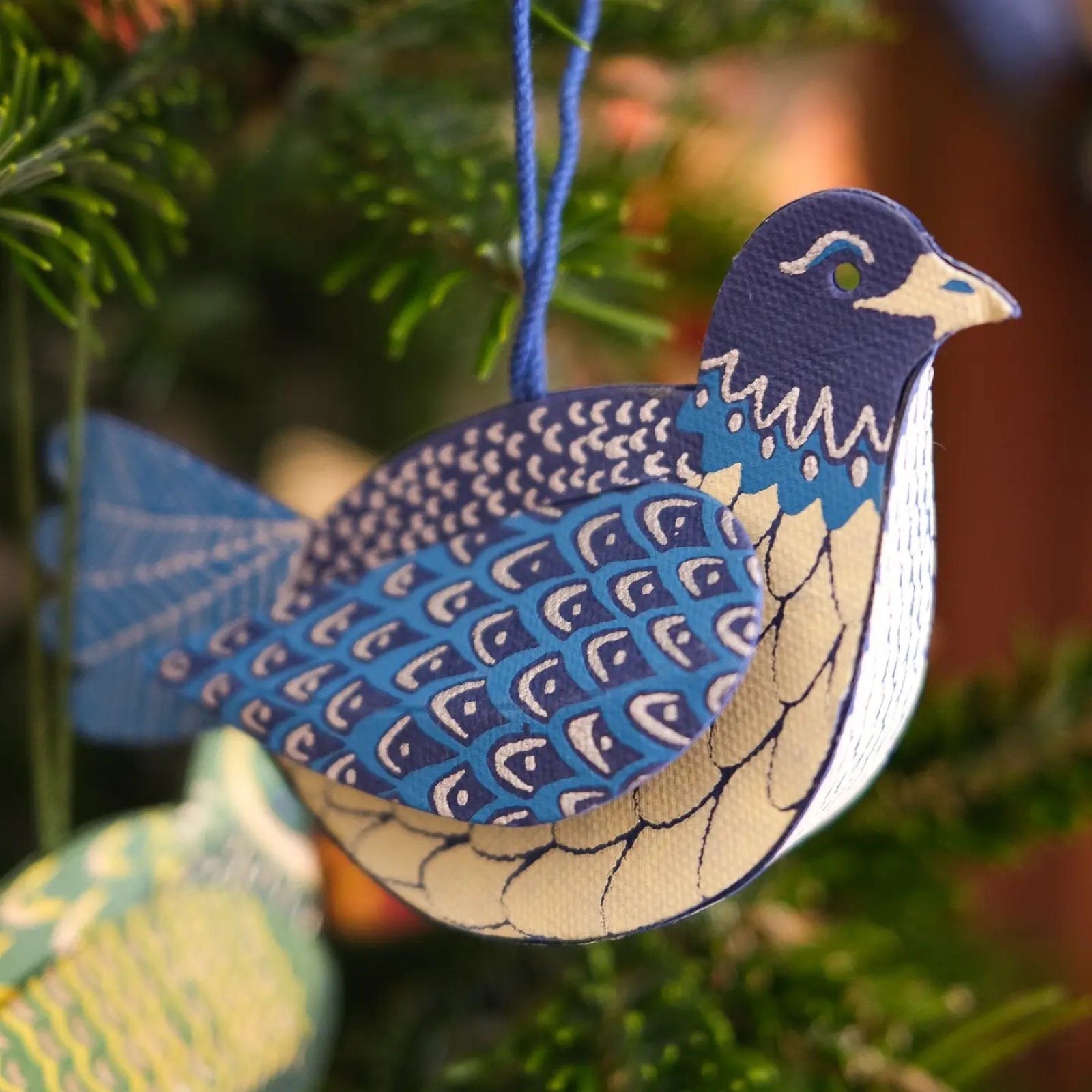 Blue 3D dove Christmas decoration hanging on a Christmas tree.