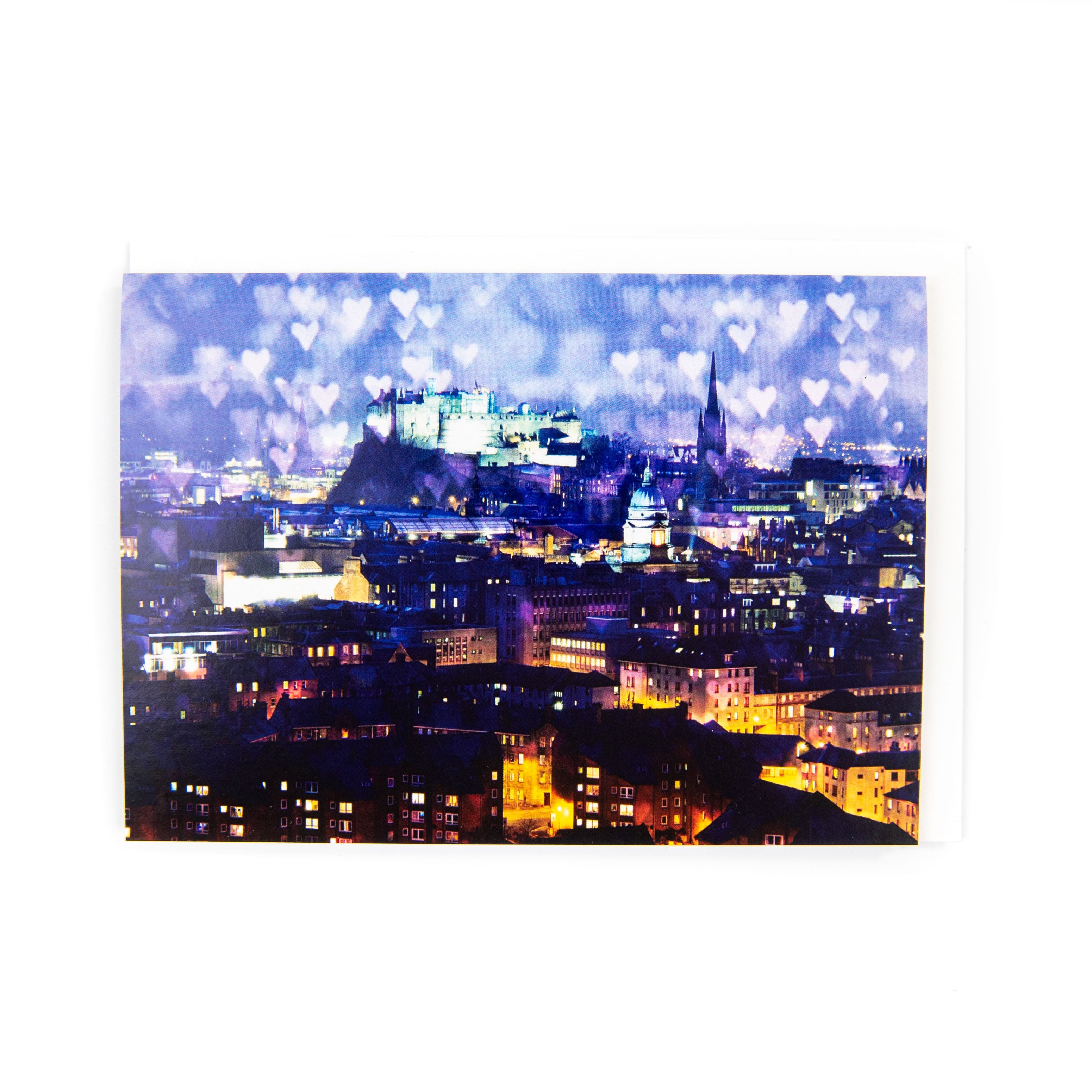 An A6 greeting card featuring a nighttime view of Edinburgh Castle with a sky filled with love hearts. The card is blank inside and comes with a white envelope.