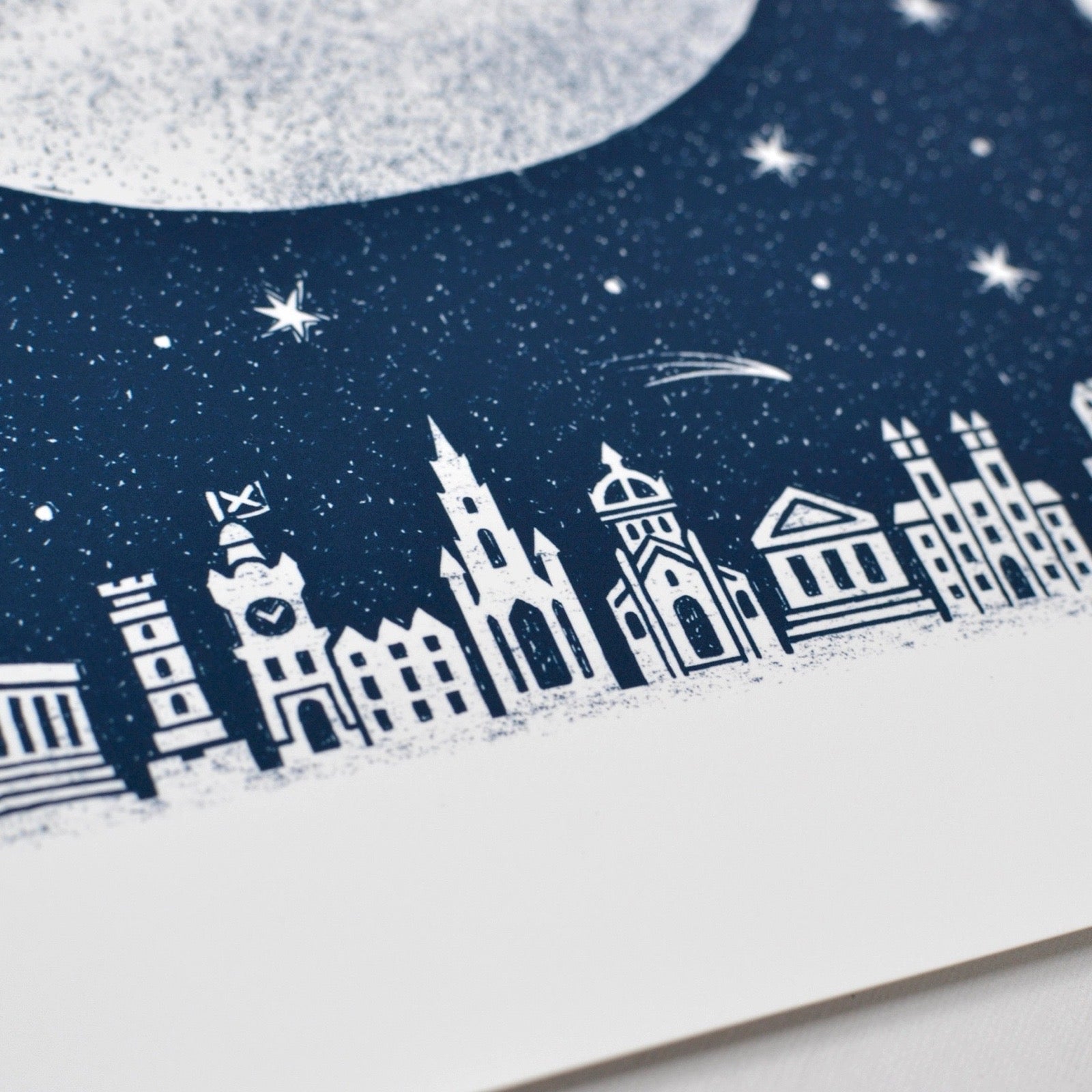 City skyline silhouette on a snowy night with stars and moon.