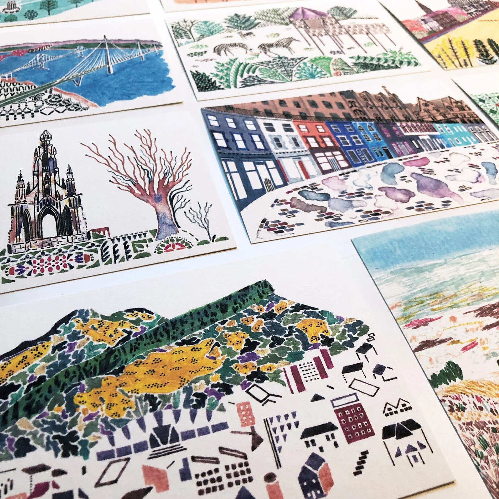 Collection of colorful illustrated postcards on a white surface.