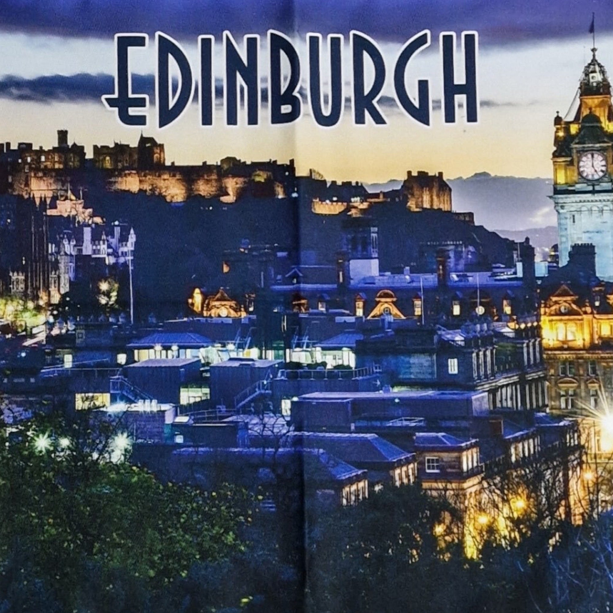 Cityscape of Edinburgh with illuminated buildings and clock tower at night.