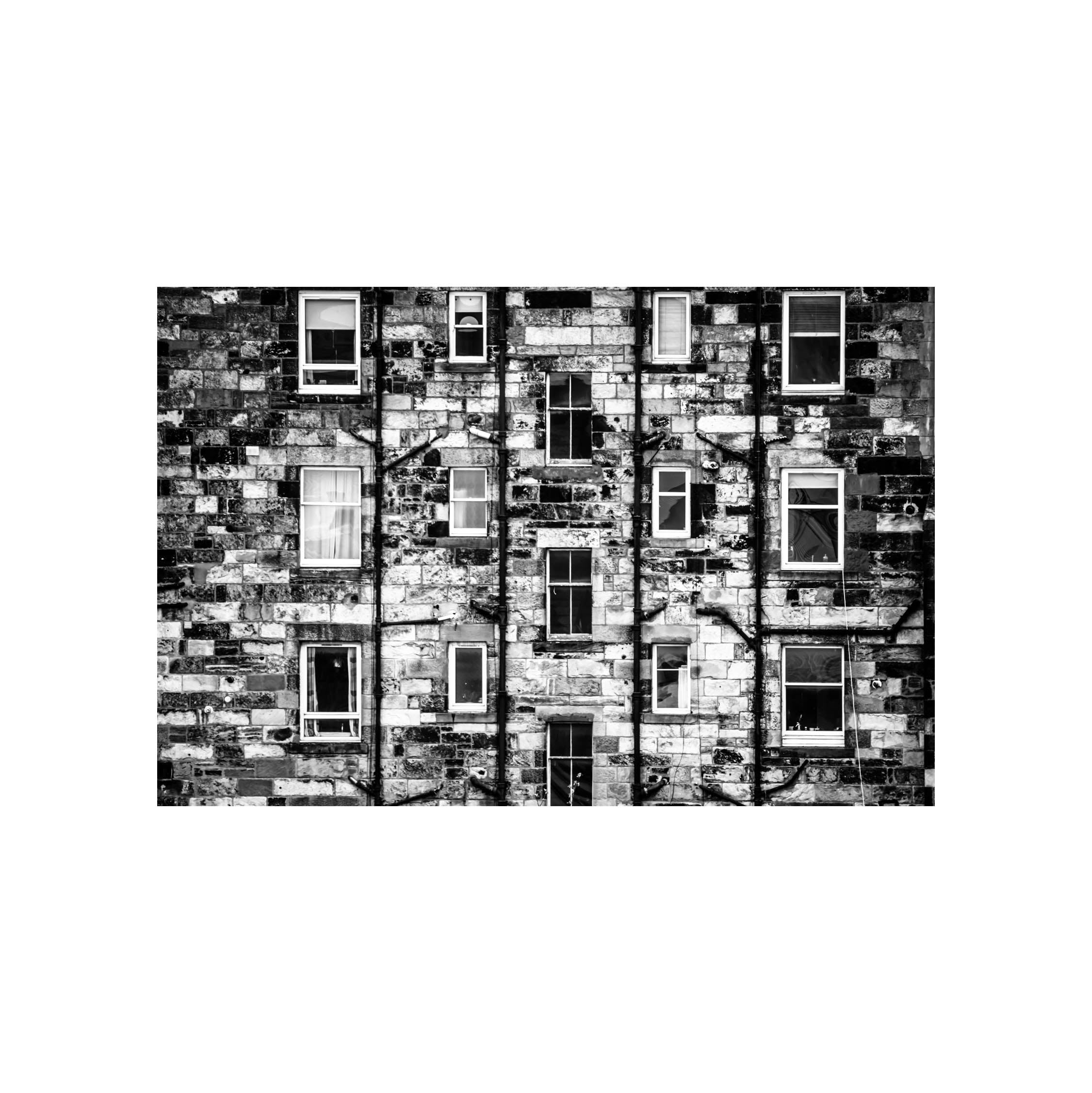 A black and white image of Edinburgh tenements showing the windows and brickwork in a square white mount. 