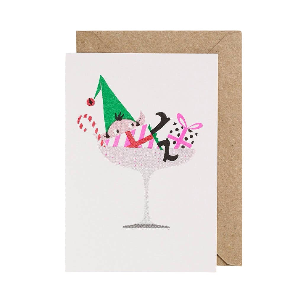 Christmas card featuring an elf lying in a cocktail glass surrounded by presents and a candy cane