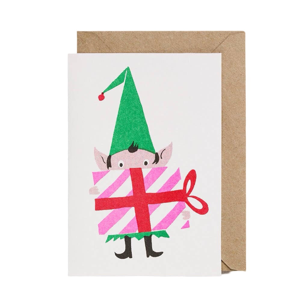 Christmas card featuring an elf holding a giant present wrapped in pink and white paper and tied with red ribbon