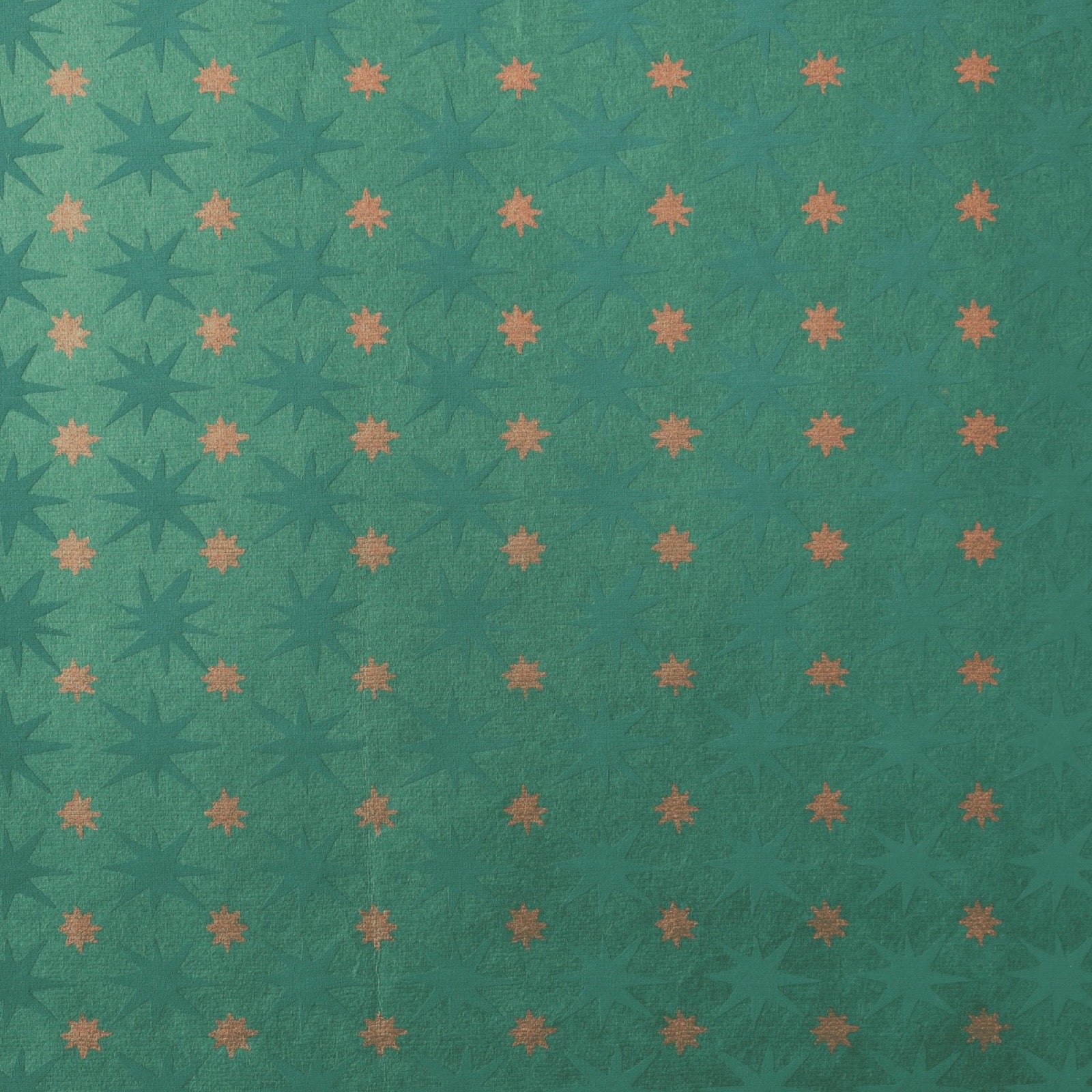 A close-up of wrapping paper featuring a repeating grid of starbursts in dark teal and muted orange on a teal-green background.