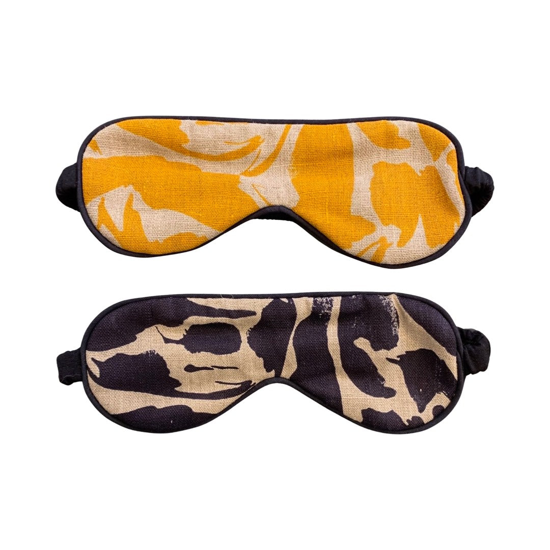 2 linen eye masks, one mustard and cream patterned, the other black and cream patterned.