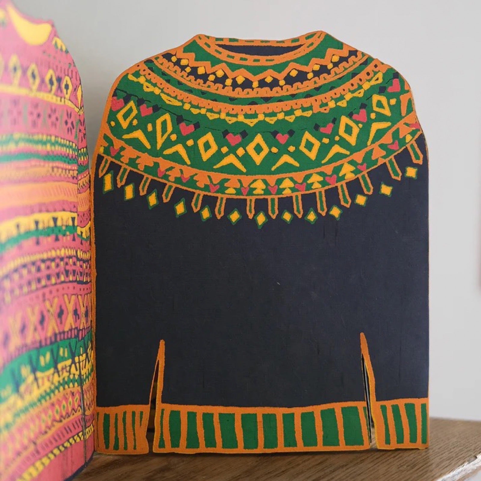 Colorful embroidered sweather with geometric patterns on a plain background.