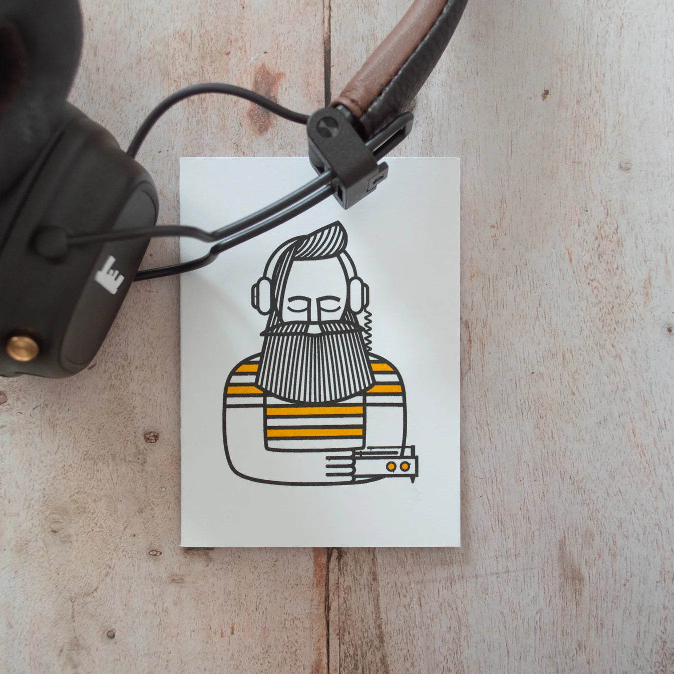 Illustration of a man listening to music, on a wooden background next to a pair of headphones.