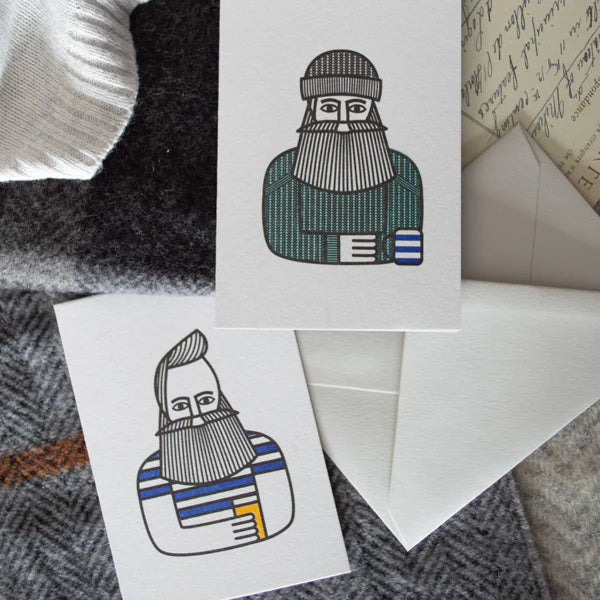 Two greeting cards with illustrations of bearded men with drinks on a textured fabric background.