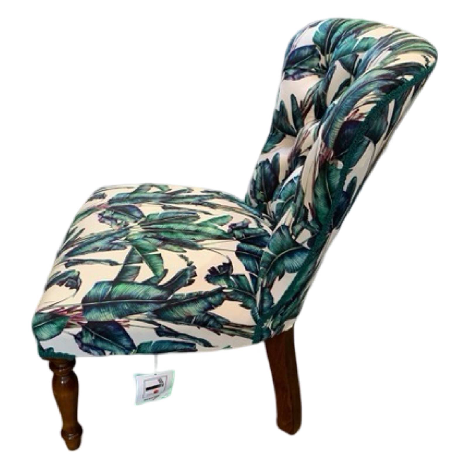 A button-back chair with off-white velvet fabric featuring a blue and green fern design, cream binding, mahogany legs, and gold castors.