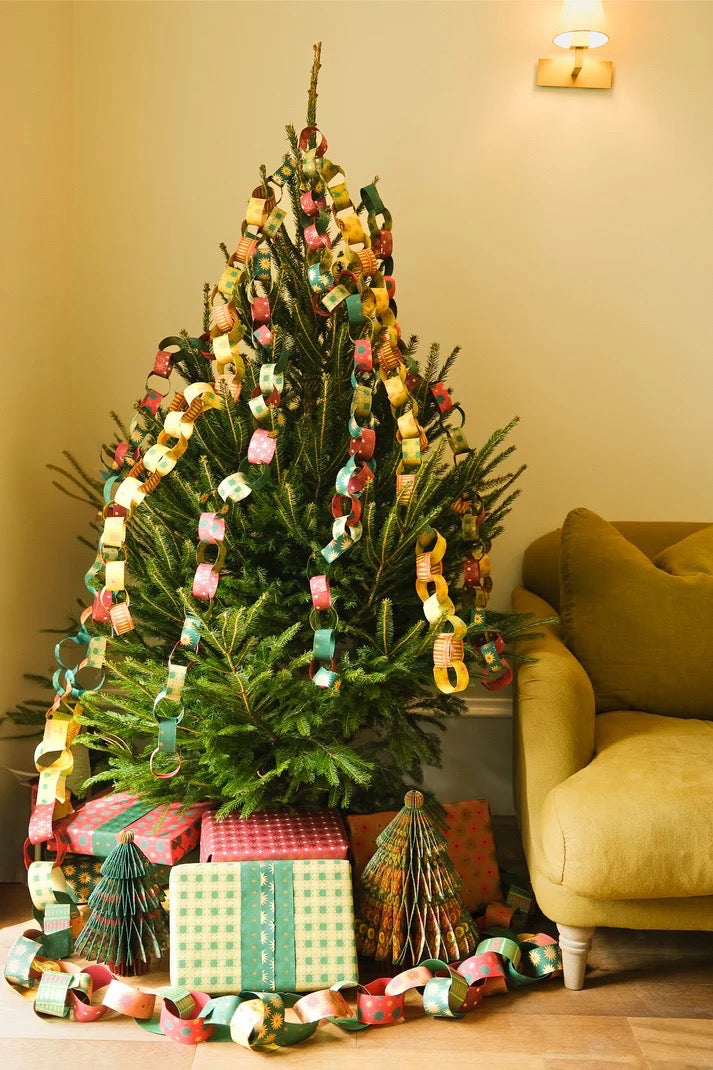 Decorated Christmas tree with colourful paper chains and presents in a living room.