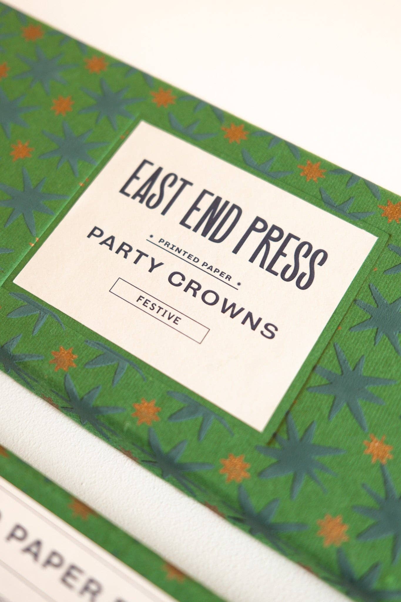Box of East End Press party crowns with green and orange design.