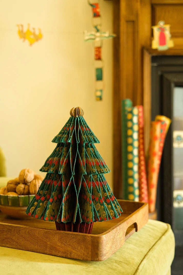 Small decorative Christmas tree on a wooden tray with a festive background.