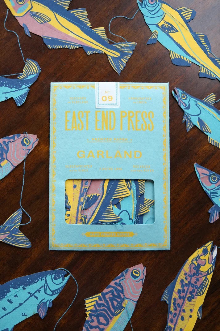 Box with 'East End Press' branding surrounded by colourful fish illustrations on a wooden surface.