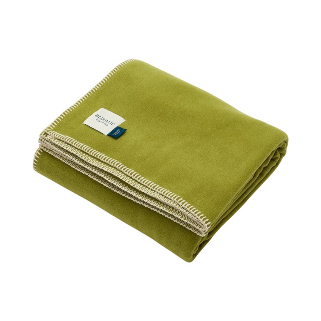 A green fleece blanket with cream stitched edges.