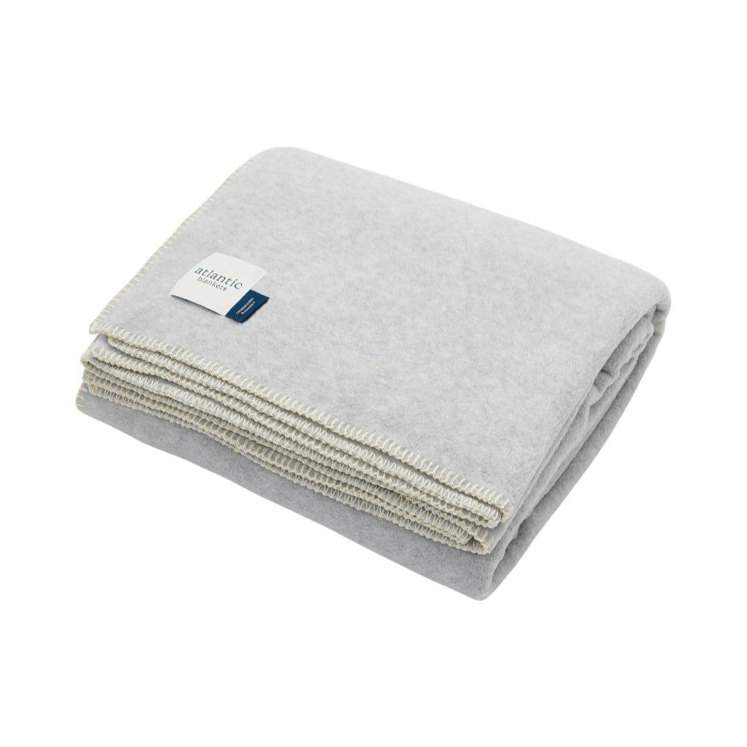 A grey fleece blanket with cream stitched edges.