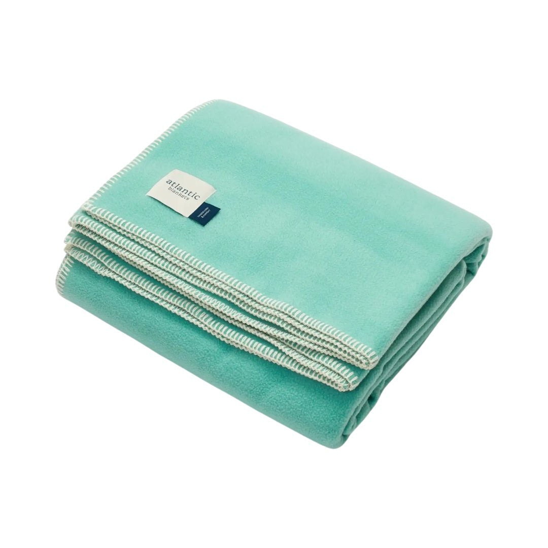 A turquoise fleece blanket with cream stitched edges.