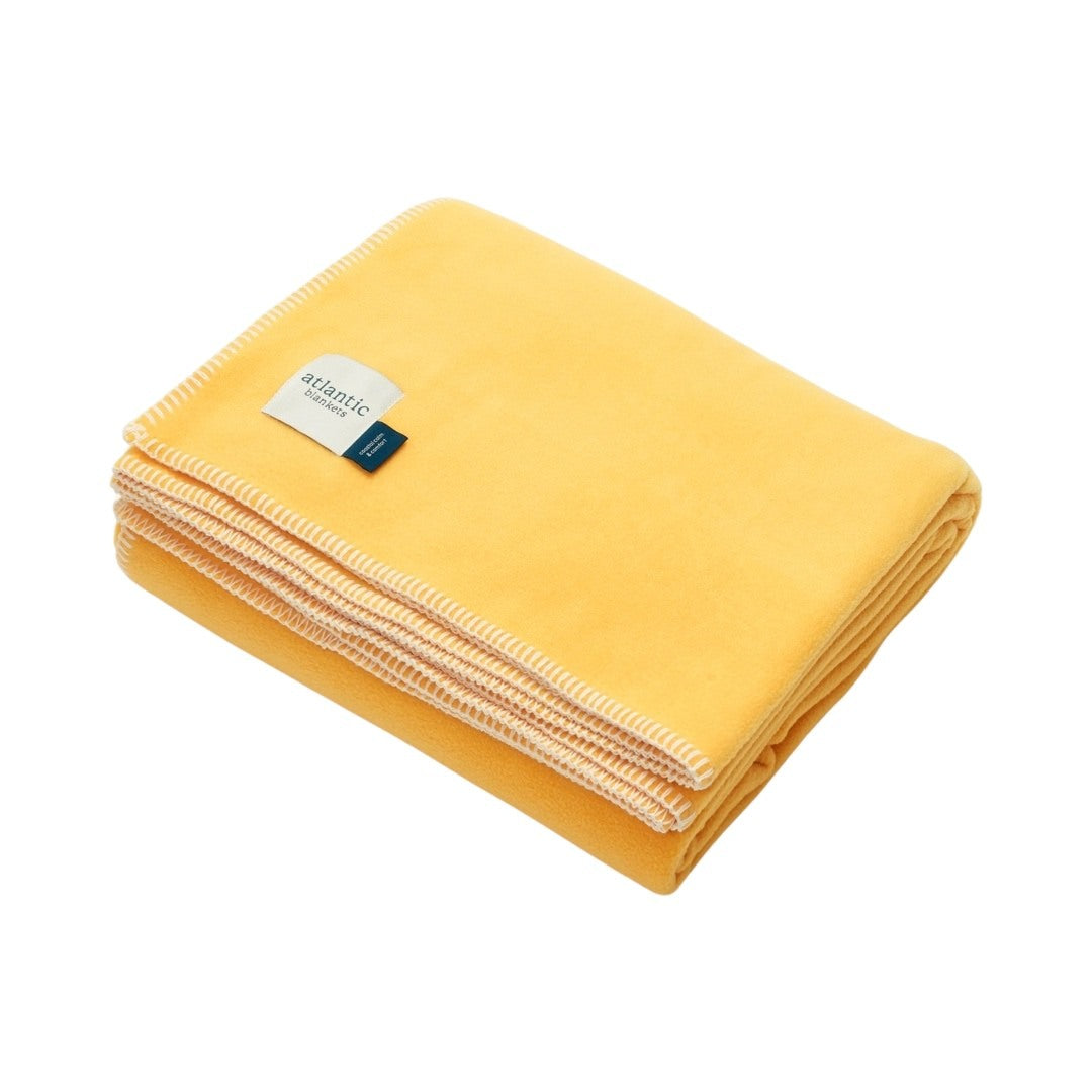 A yellow fleece blanket with cream stitched edges.