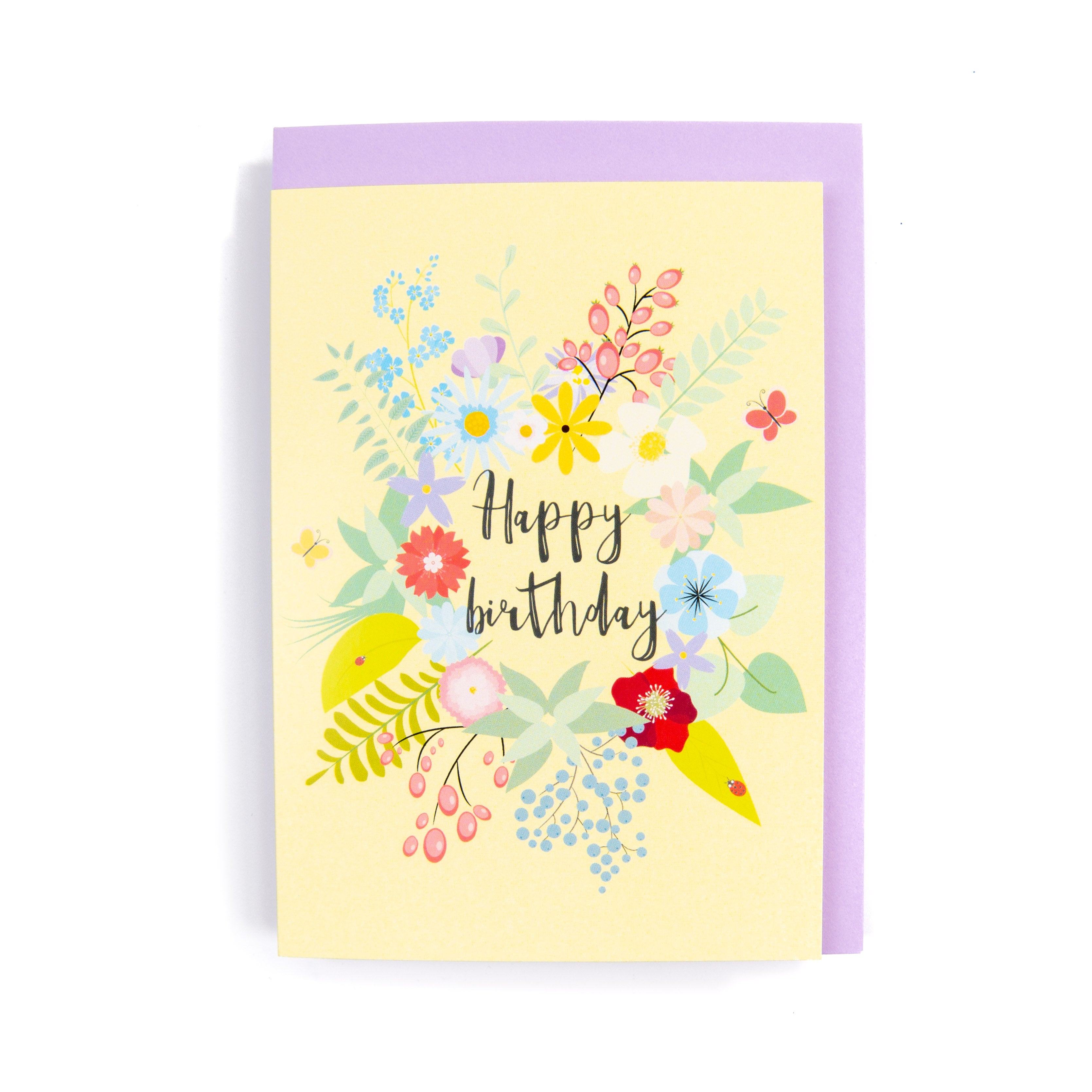 A floral birthday card with a variety of colourful flowers and the text 'Happy birthday' in the centre, presented with an purple envelope.