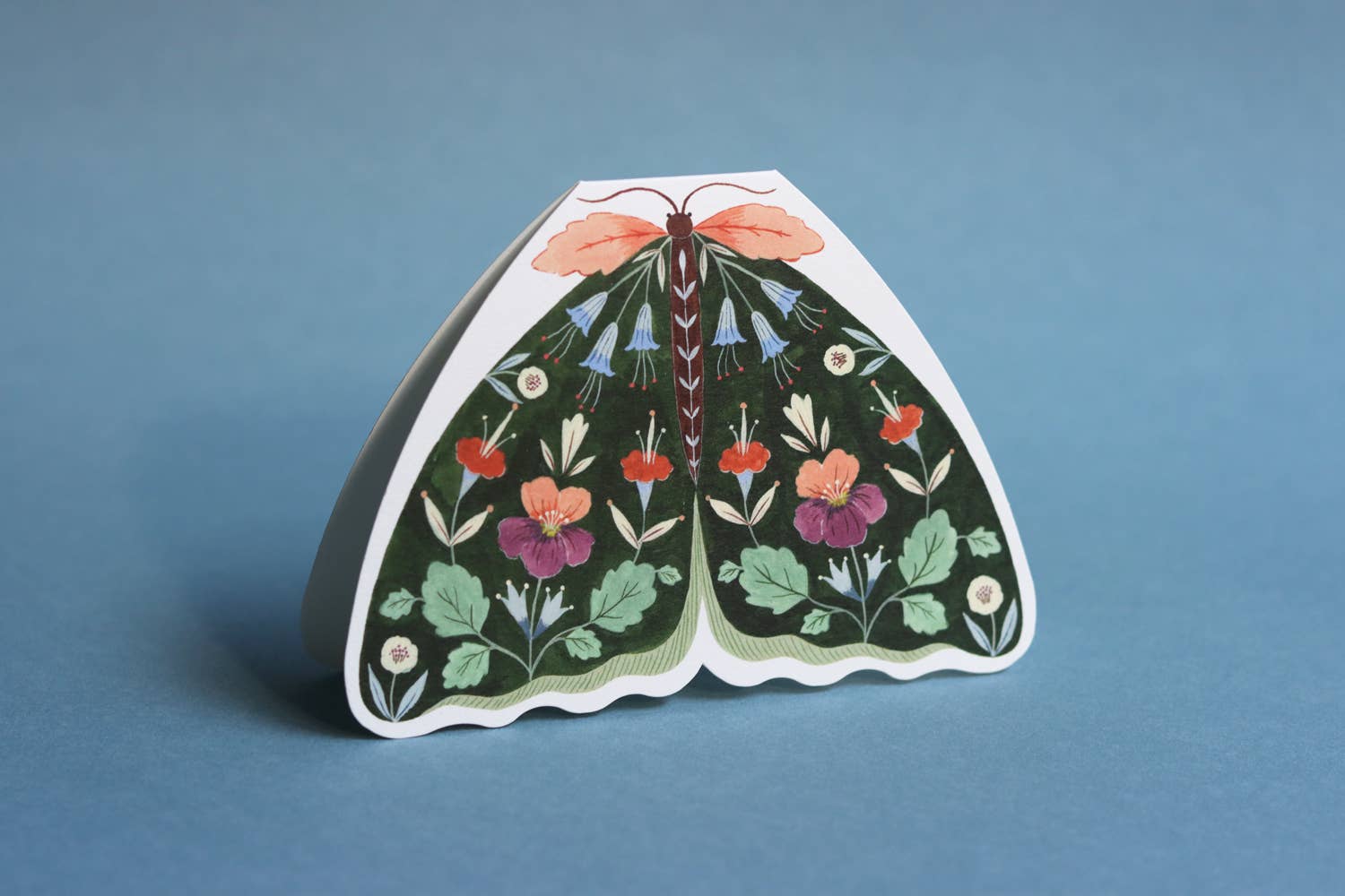 Decorative paper moth card with floral patterns on a blue background.