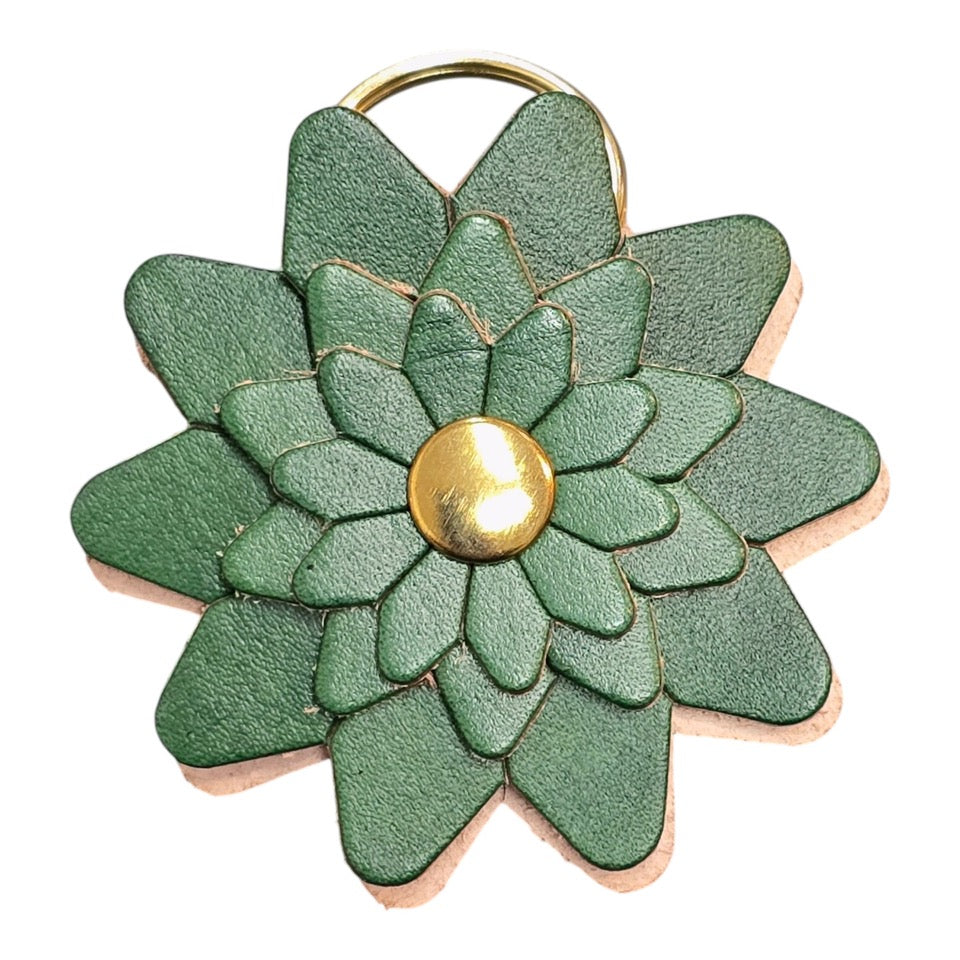 Green leather flower-shaped keyring with a gold rivet and gold ring.