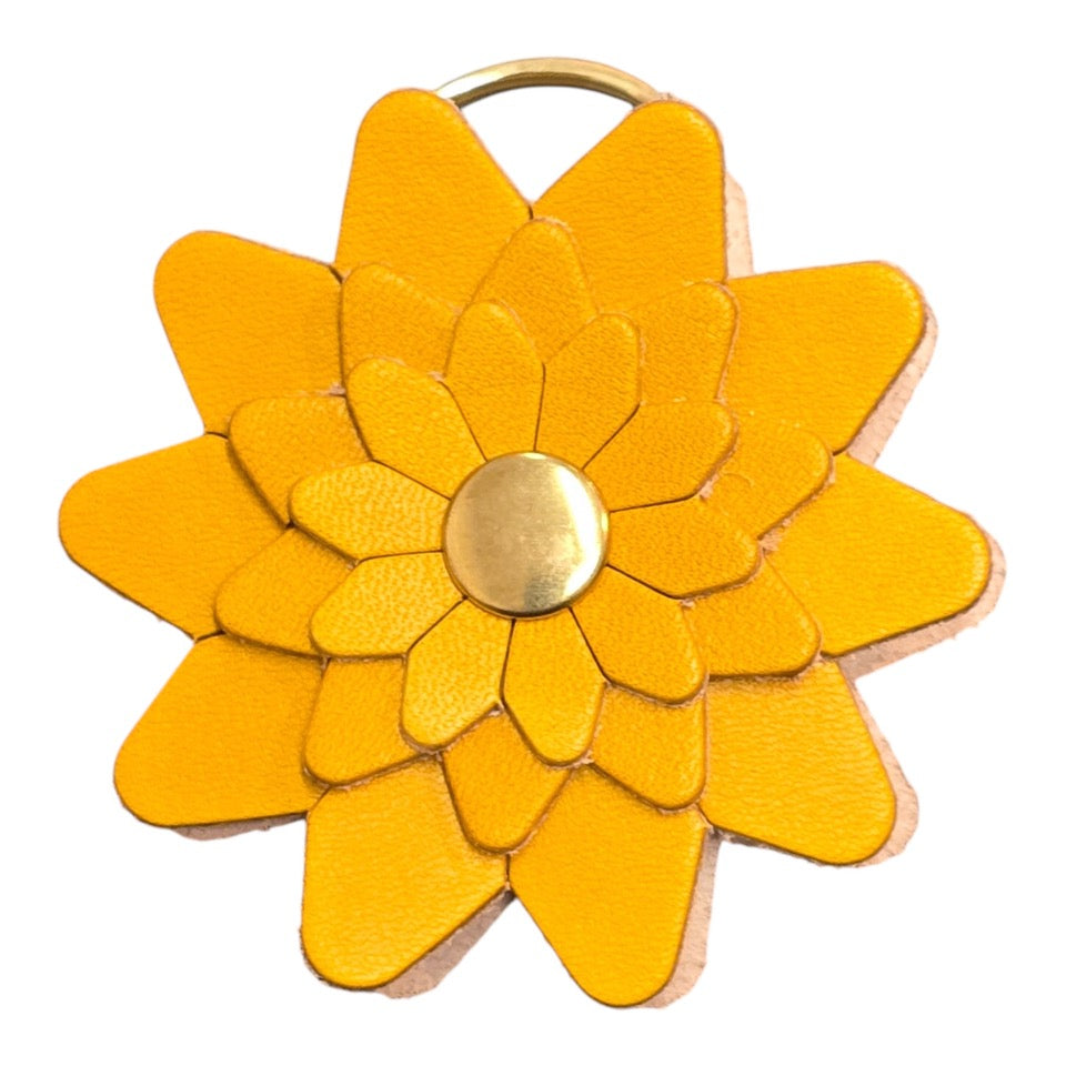 Yellow leather flower-shaped keyring with a gold rivet and gold ring.