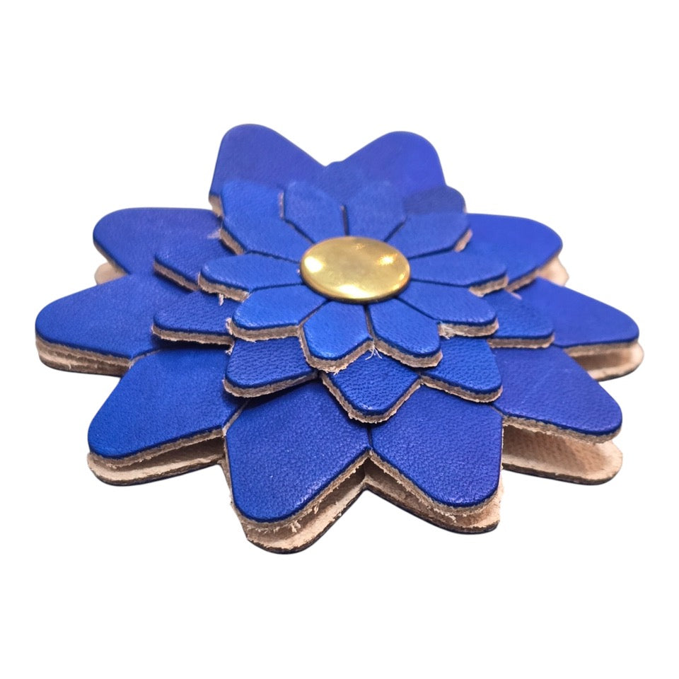 The side of a blue leather flower-shaped keyring with a gold rivet.