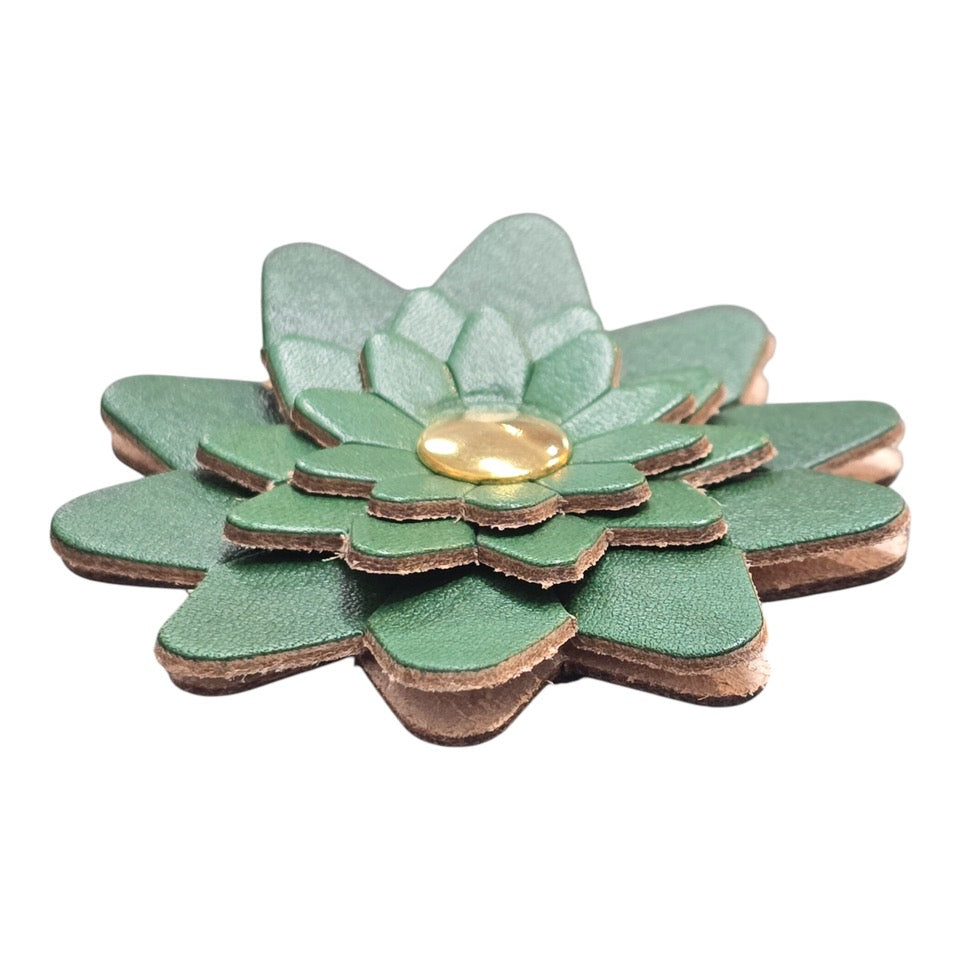 The side of a green leather flower-shaped keyring with a gold rivet.