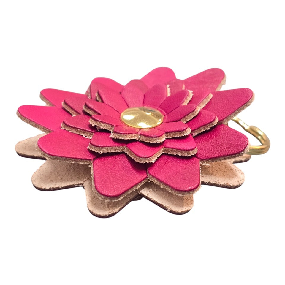 The side of a red leather flower-shaped keyring with a gold rivet.