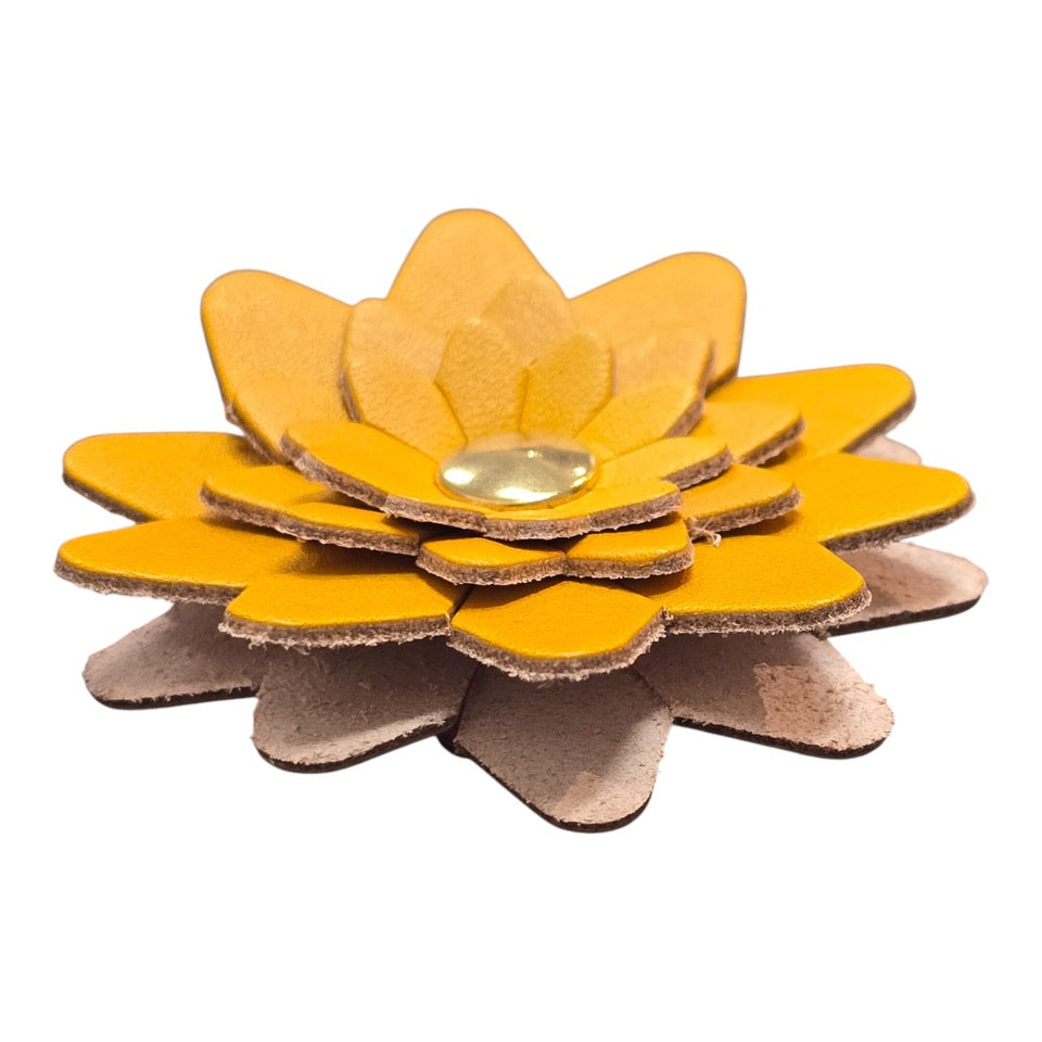 The side of a yellow leather flower-shaped keyring with a gold rivet.