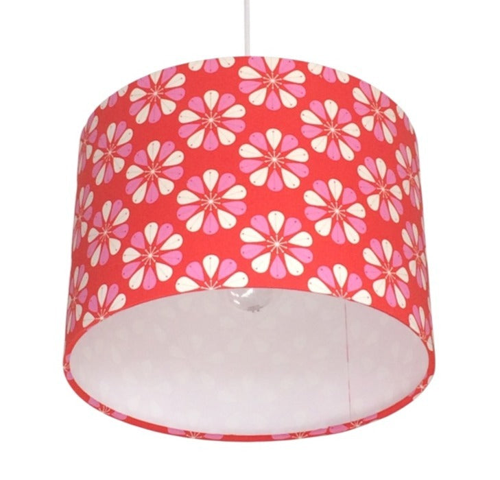 Close up of a drum lampshade featuring a red background with pink and white flowers.