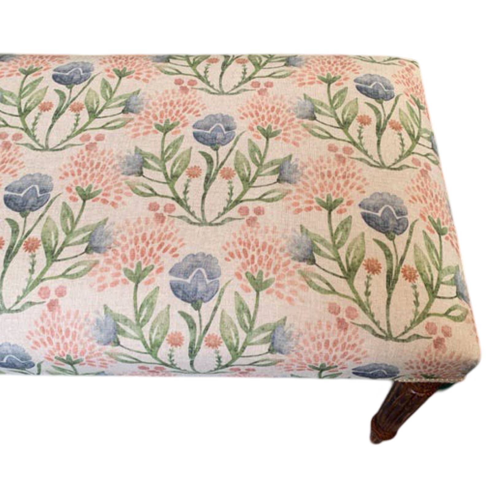 A rectangular bench with mahogany legs and a linen fabric cover featuring a floral pattern in pink, blue, and green.