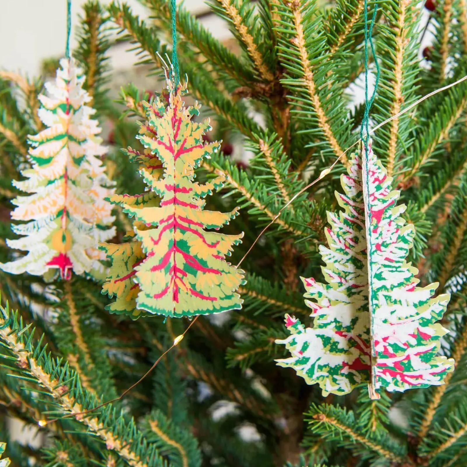 Paper tree shaped decorations hanging from a Christmas tree.